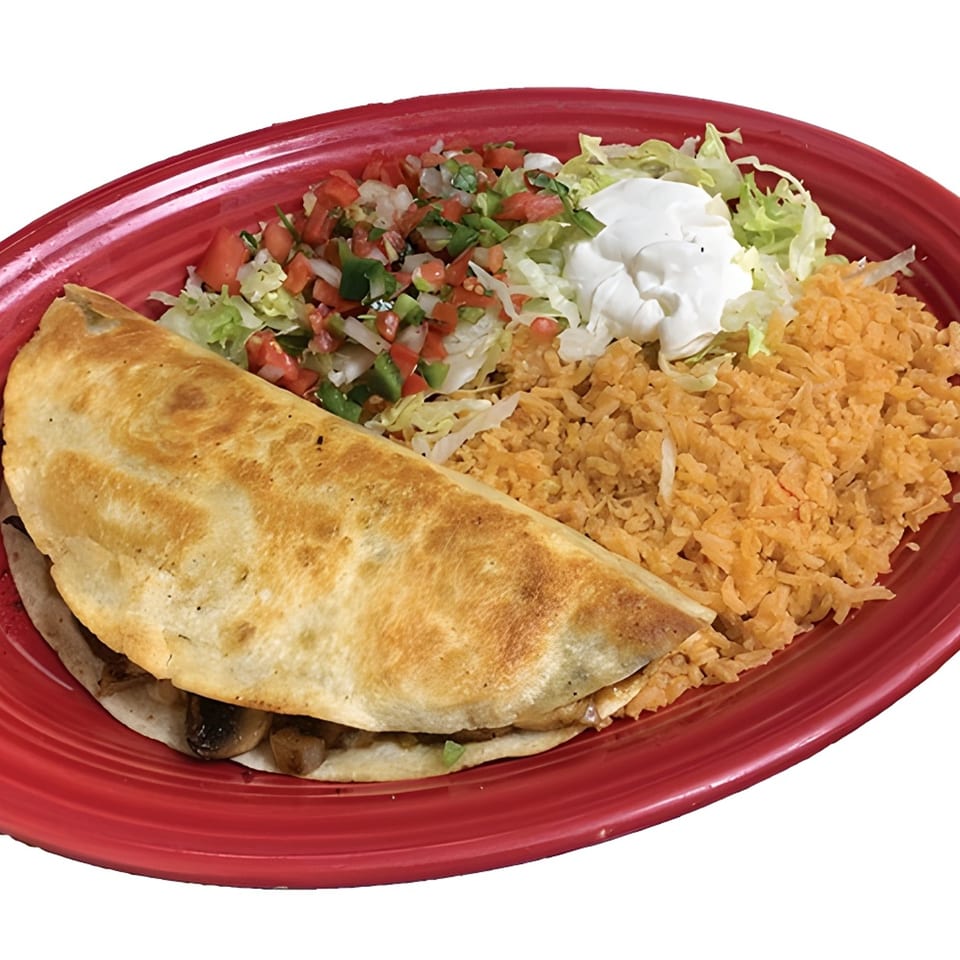 A La Carreta quesadilla with rice, pico de gallo, shredded lettuce, and sour cream on a red plate.