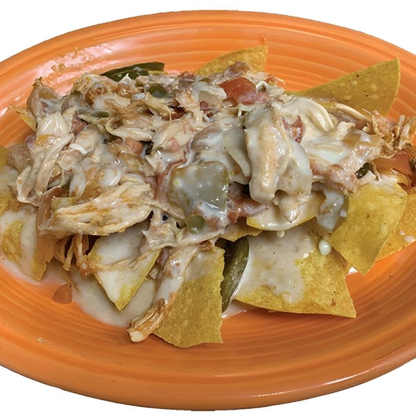 La Carreta's chicken nachos with creamy white cheese sauce, jalapeños, and tomatoes on an orange plate.