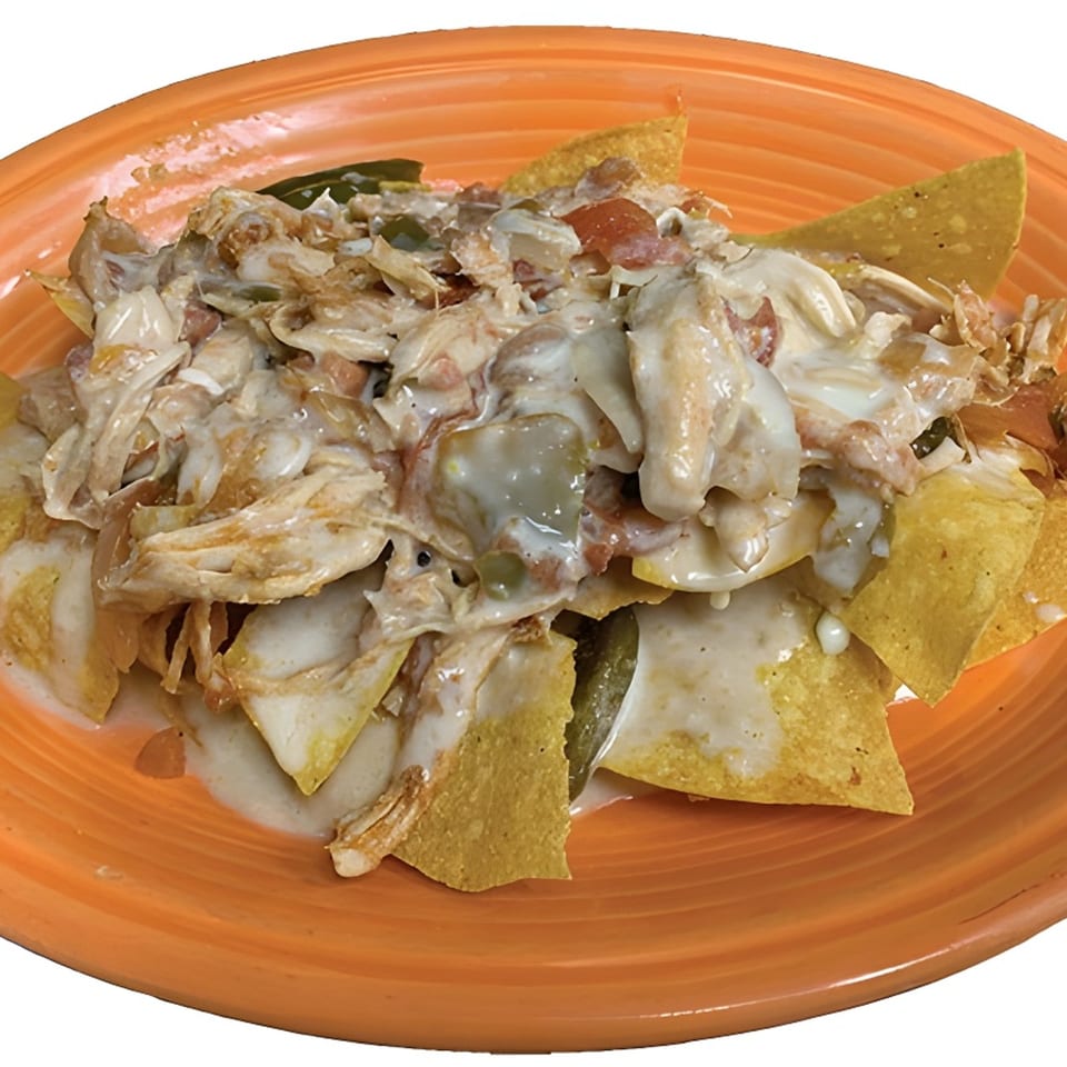 La Carreta's chicken nachos with creamy white cheese sauce, jalapeños, and tomatoes on an orange plate.